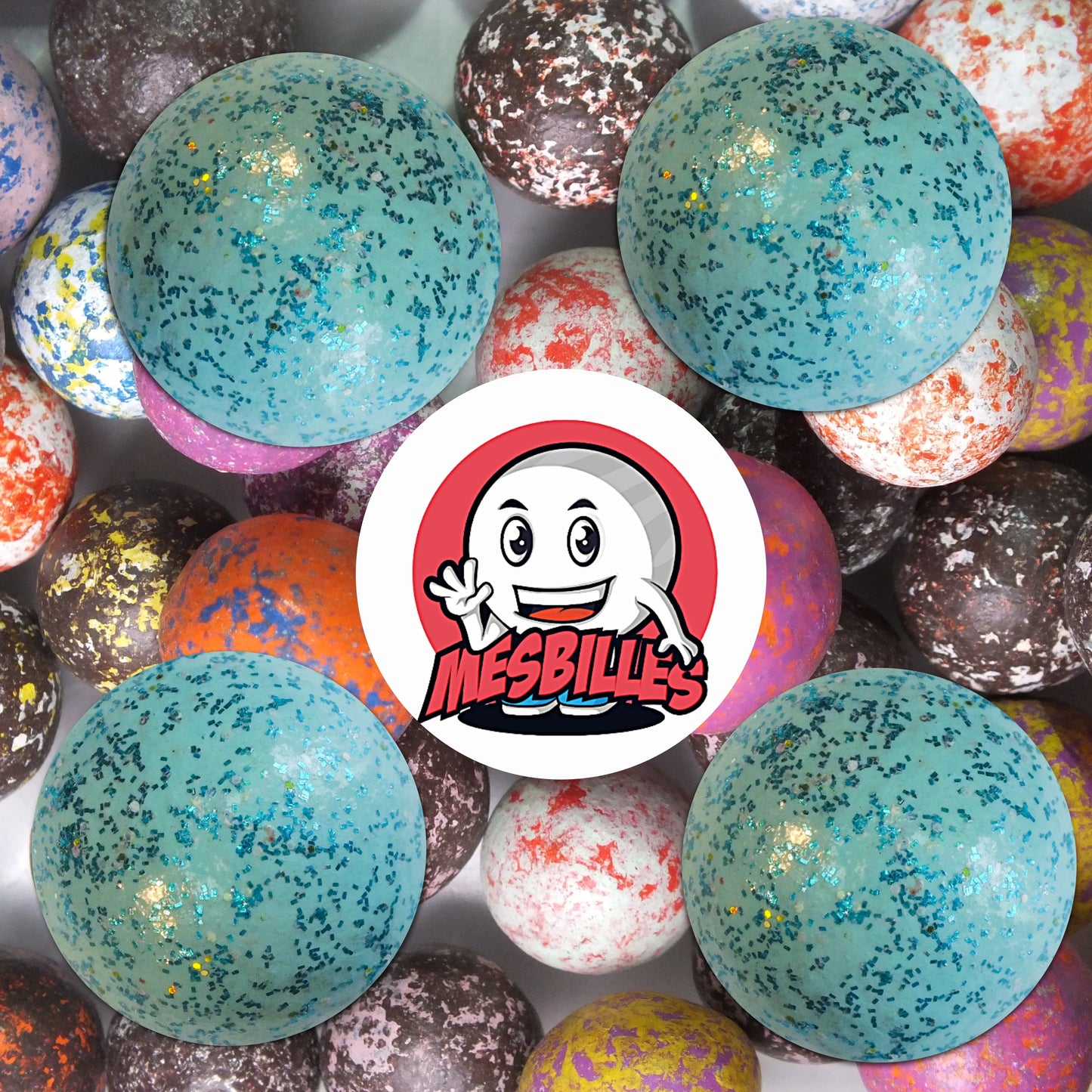 Collection de billes en terre multicolores avec plusieurs billes bleu paillettes 22 mm au premier plan, ambiance ludique et brillante