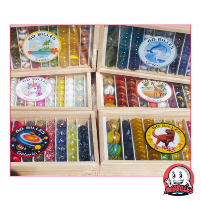 Photo des 6 coffrets bois Kim'Play par MesBilles, réunissant 360 billes aux thèmes Océan, Savane, Licorne, T-Rex, Galaxie et Exotic – un tour du monde (et de l’espace) en verre coloré.