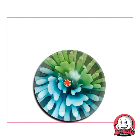 Admirez la bille Art Pissenlit Bi-Couleurs Bleus 25 mm : une bille artistique en verre avec un motif floral bleu et vert évoquant un pissenlit en pleine dispersion. Chaque bille présente des nuances uniques.