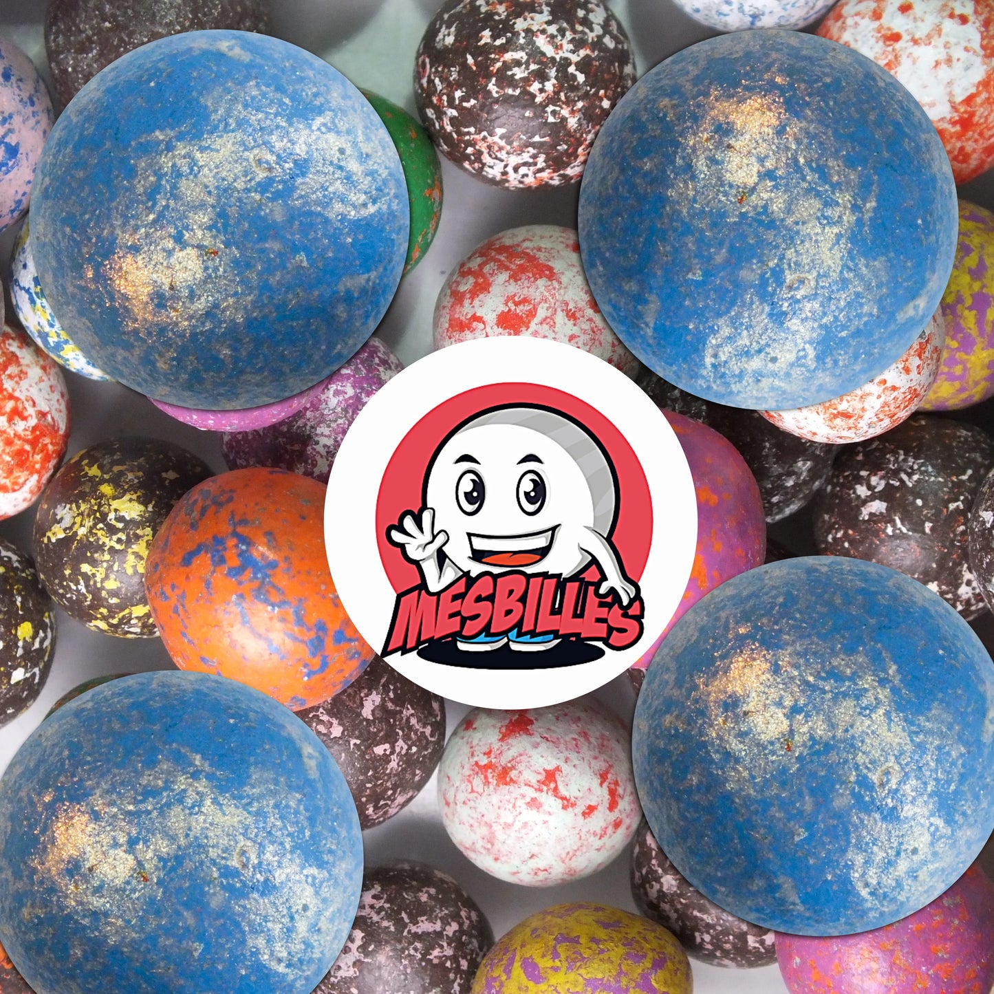 Collection de billes en terre multicolores avec plusieurs billes bleu clair moucheté 25 mm au premier plan, ambiance élégante et ludique.